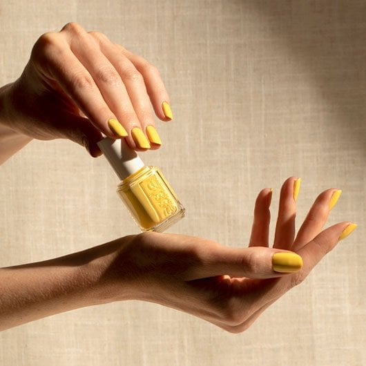 two light skin hands wearing and handling a bottle of meditation haven cream yellow nail polish