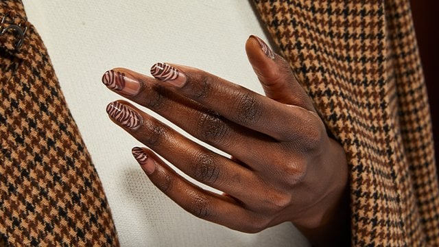 woman in tweed with brown zebra stripe nails manicure