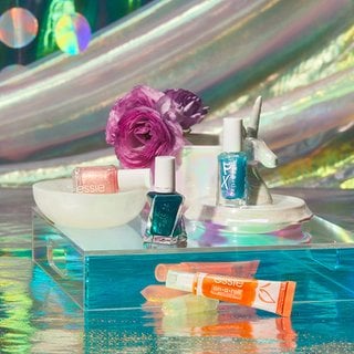 shimmer and glitter essie nail polish bottles with accessories on reflective background
