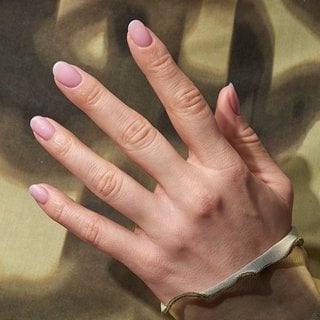 Hand outstretched against a green background with lip gloss manicure on the nails
