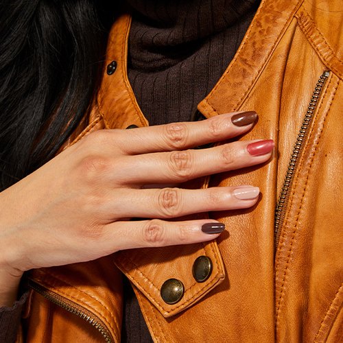 hand with nails painted in multi-colored brown nail polish shades