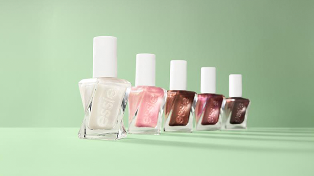 5 essie nail polish bottles of varying colors lined up on a green background 