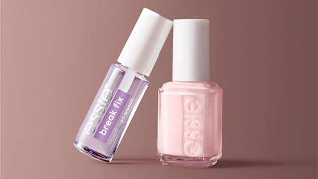 Lavender essie nail polish bottle leaning against a pink essie nail polish bottle