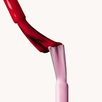 Pink and red wet nail brushes meeting on a white background