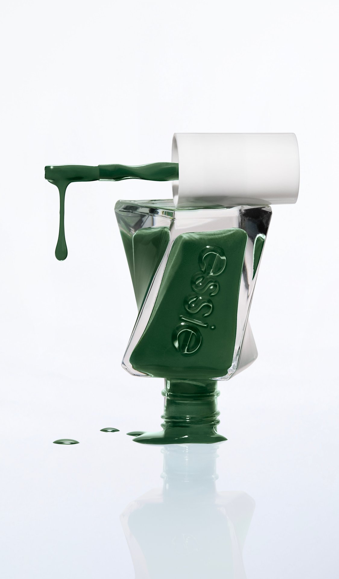 An inverted, twisted bottle of Gel by essie nail polish in shade "In-vest In Style" with a thick droplet hanging from the brush.