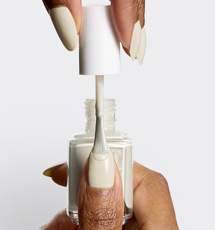 Close-up of a brush applying a nail polish in shade "Marshmallow" to a fingernail, showing the smooth texture.