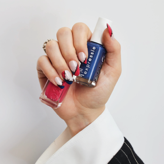 light skin hand featuring zany zombie nail art holding two bottles of expressie nail polish