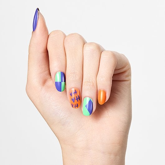 hand featuring orange, green, and purple halloween nail art with a different design on each nail