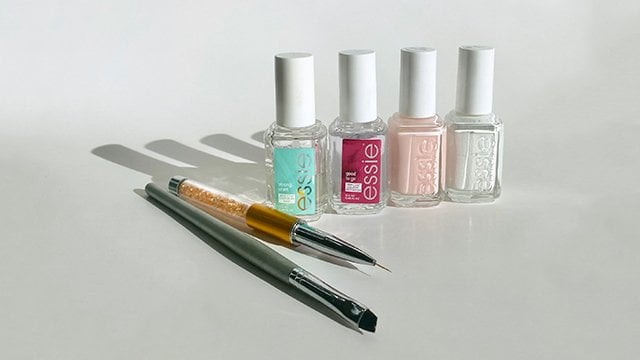 Four bottles of nail poilish with two nail art tools
