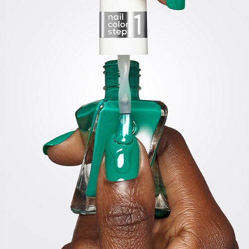 An open bottle of green gel nail polish held by a dark skin hand while brushing it on a thumbnail