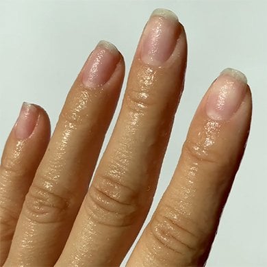 Four upright fingers on a light skin hand with nude nails that are clean and shaped
