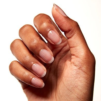 Medium skin hand with fingers folded over palm showing nude nails a little wet after washing