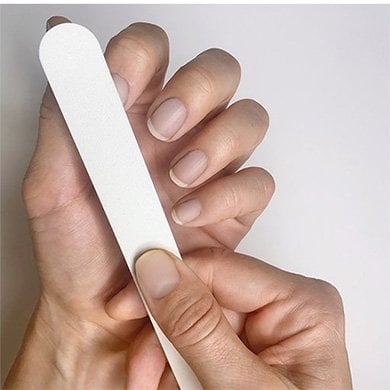 Nude nails on light skin hands, with surface of the index fingernail being buffed.