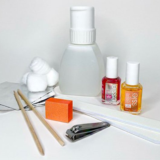 Supplies for removing gel nails like clippers, files, foils, and nail hardeners on a white background