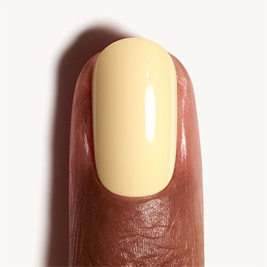 Closeup of dark skin fingernail wearing light buttercup yellow Atelier At The Bay essie polish