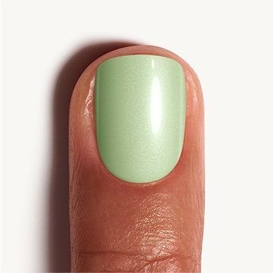 Closeup of medium skin fingernail wearing pistachio green Bling It essie nail polish