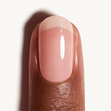 closeup of light skin fingertip and nail painted in a pearlescent white essie nail polish