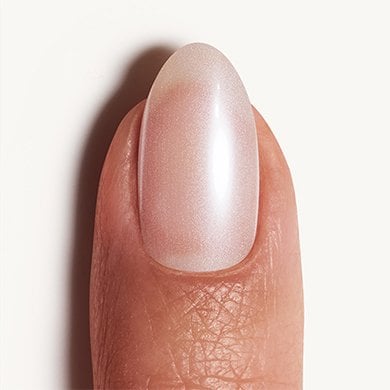 dark skin fingernail against white background wearing a sheer white essie nail polish
