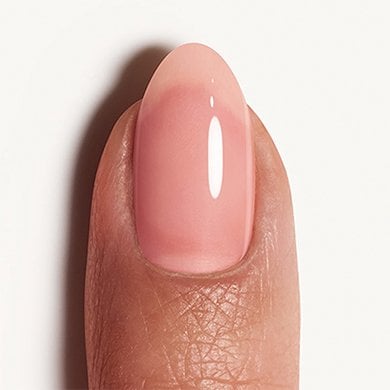 Light skin fingertip with nail painted in sheer pink 'sugar daddy' essie polish
