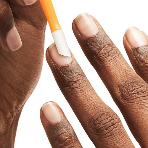 Dark skin hand holding an orange & white cuticle pusher and working on the other hand's cuticles