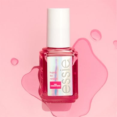 Pink puddle on a pink surface with bottle of hard to resist glow & shine on its side