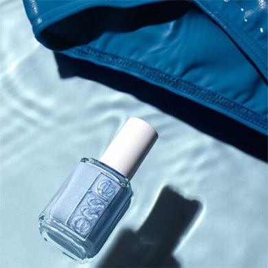 shallow pool, bottle of blue essie polish floating near a submerged blue bathing suit