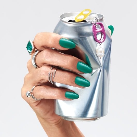 hand with nails in the shade dopamine rush crushing a soda can
