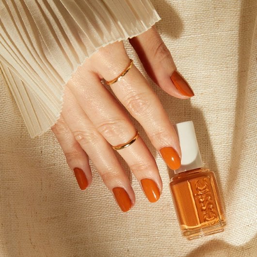 light skin model touching a bottle of cream orange sol searching nail polish and wearing the shade