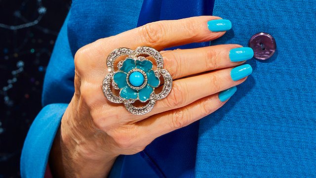 Woman with seagreen teal solid color manicure wearing a blue green flower ring