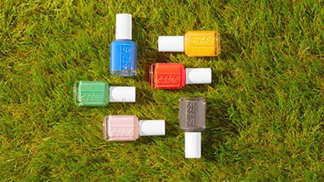 Six bottles of nail polish in the shades from the push play collection laid at different angles on a grass background