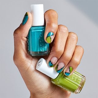 blue and green nail polish bottles held by a medium skin hand with monster nail art