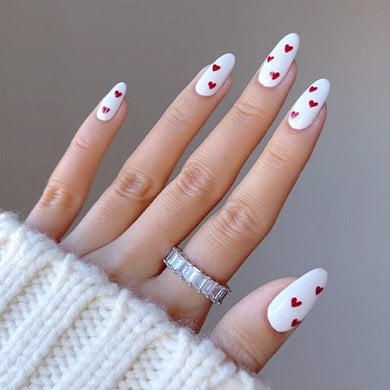 hand with white manicure and red nail art wearing a silver ring