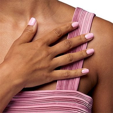 model wearing a pink top with nails painted in essie baby pink nail polish