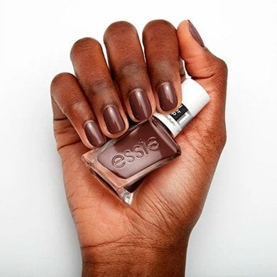 hand holding essie all checked out nail polish on a white background