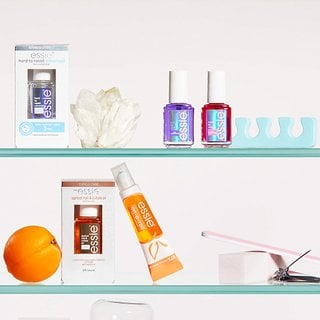 two glass shelves with white background, one shelf with three essie nail strengtheners (one clear, one purple, one pink), a white crystal rock and blue pedicure tool and one shelf with two essie apricot cuticle oils, an apricot, silver nail clipper, white nail buffer and pink nail file