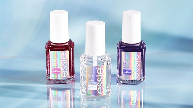 three essie nail strengthener polish bottles (one pink, one clear and one purple) standing up with reflections on a blue and iridescent background