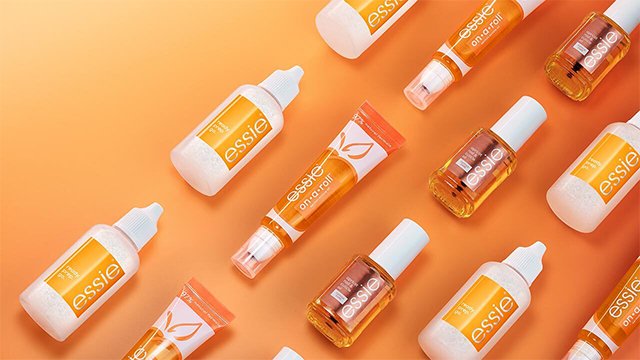 Line up of essie's cuticle oils laid out against a bright orange background
