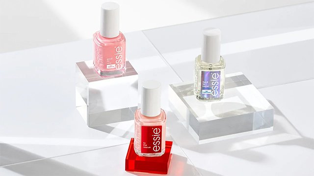 Bottles of essie nail treatments on pedestals against a white geometric background