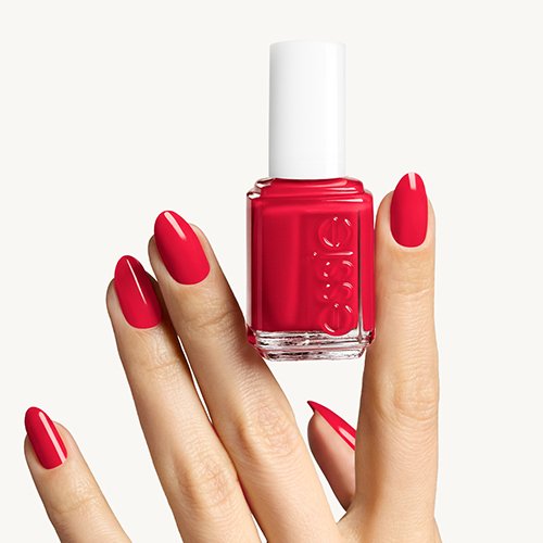 Red polish on light skin hand holding the bottle between index and middle fingers