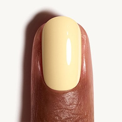 Closeup of a dark skin fingertip painted in pastel yellow nail polish Atelier at the Bay