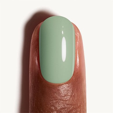 Closeup of a medium skin fingertip painted in pastel mint green nail polish Crunch Crunch