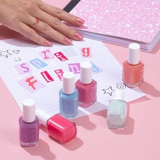 Essie nail polish bottles in spring colors with a spring fling poster and notebook in the background